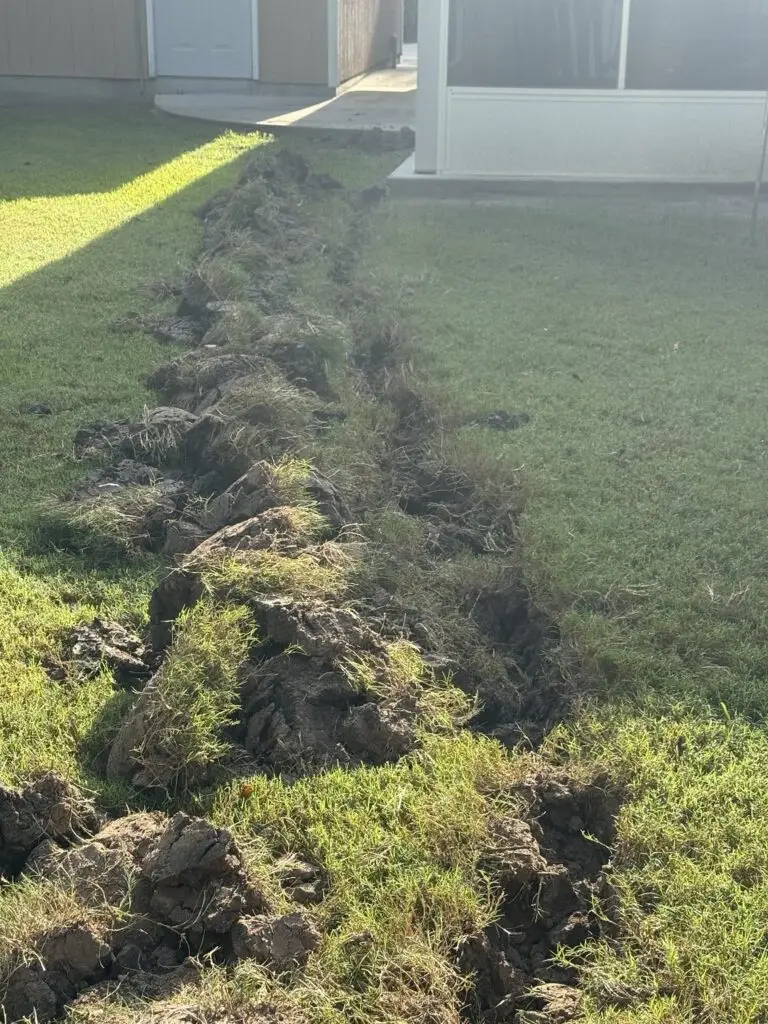 Backyard trench extending toward a home during an underground gas line replacement in Breaux Bridge, Louisiana