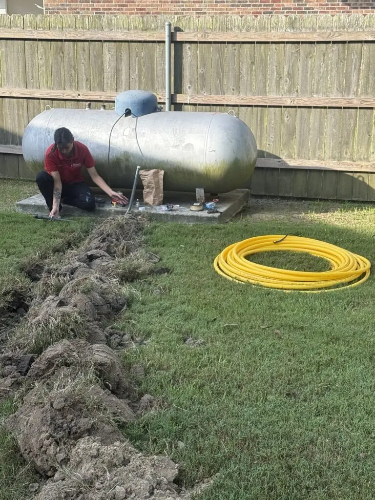 Michael B Plumbing technician installing a gas line near a residential propane tank in Breaux Bridge, Louisiana