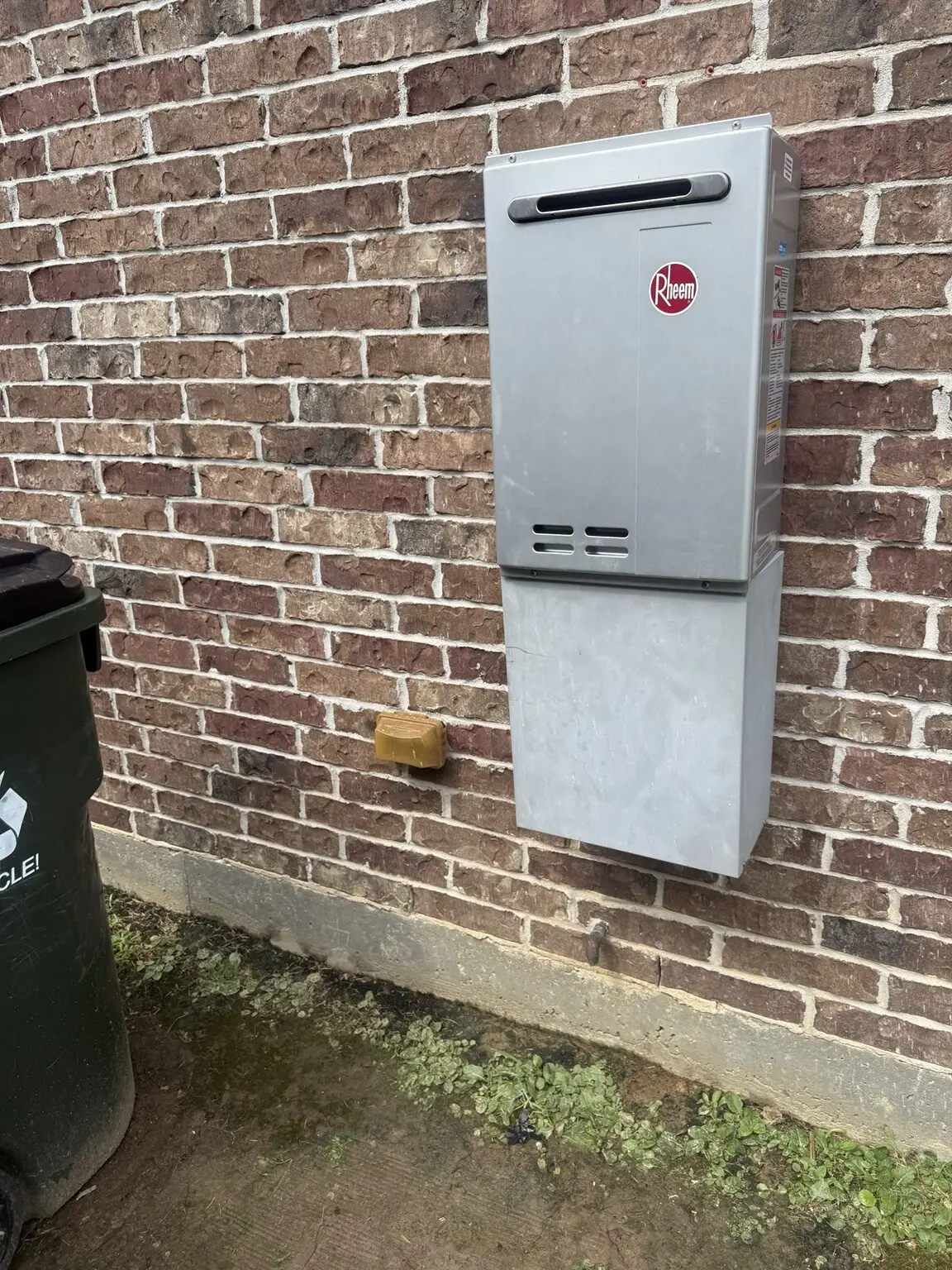 Completed outdoor Rheem tankless water heater replacement mounted on a brick home in Lafayette, Louisiana