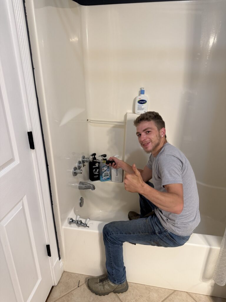 Michael B Plumbing technician working on a three-handle to single-handle tub and shower faucet conversion in New Iberia