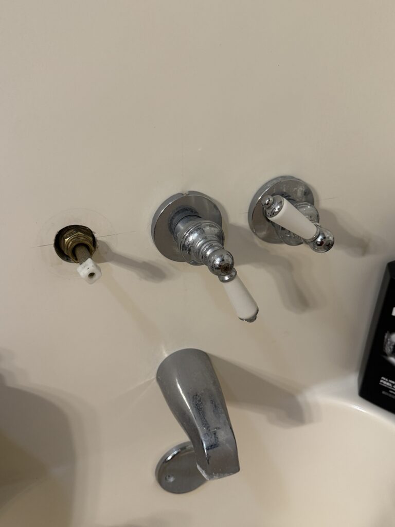 Before photo of an older three-handle tub and shower faucet in New Iberia, Louisiana