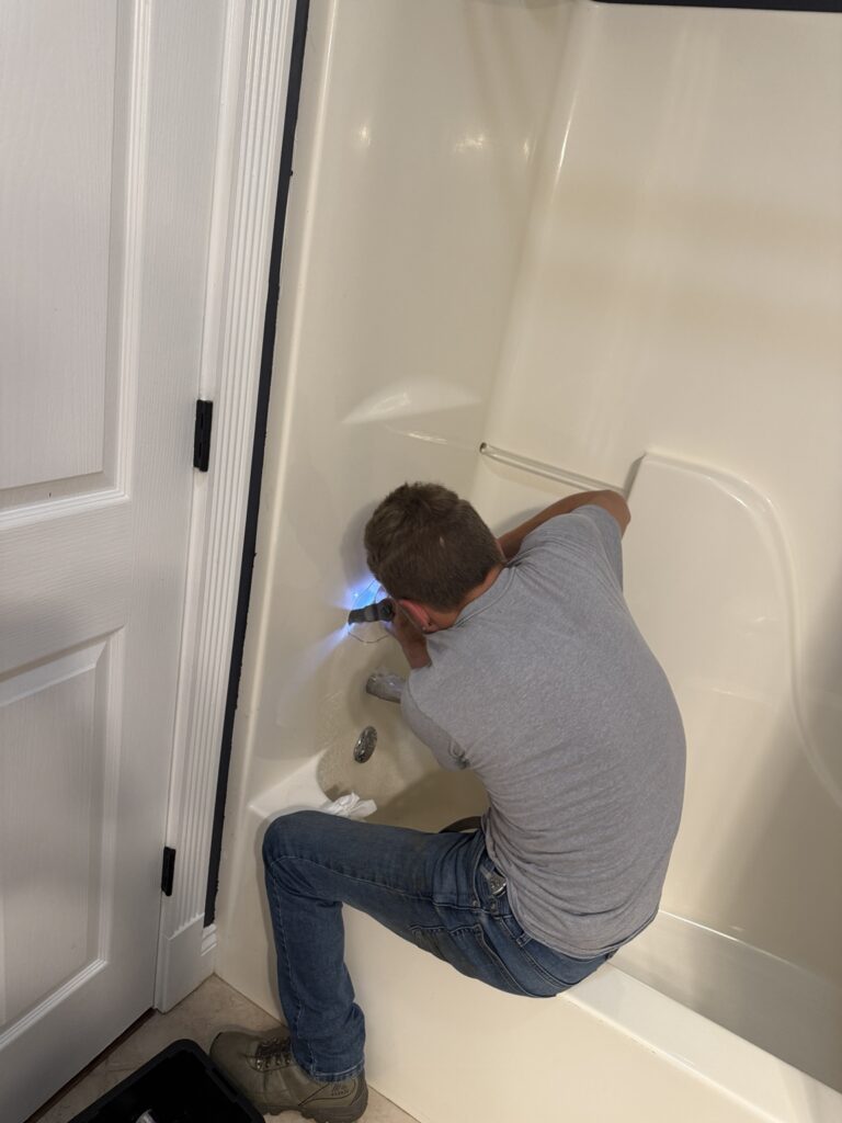 Plumbing technician opening the tub surround for a single-handle shower valve conversion in New Iberia